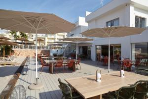 a patio with tables and chairs and umbrellas at Can Salia in San Antonio Bay