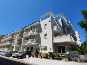 an apartment building with cars parked in front of it at Hotel Des Bains in Cattolica