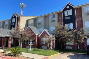 an apartment building with trees in front of it at Super 8 by Wyndham San Antonio Downtown NE in San Antonio