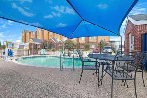 a table and chairs under an umbrella next to a pool at Super 8 by Wyndham San Antonio Downtown NE in San Antonio