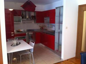 a kitchen with red cabinets and a white table at Apartment 4 you in Split