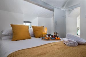 a white bedroom with a white bed with yellow pillows at The Little Cottage in Bryn-crug