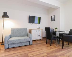 ein Wohnzimmer mit einem Stuhl, einem Tisch und einem TV in der Unterkunft Regina Maris by Baltic Home in Świnoujście