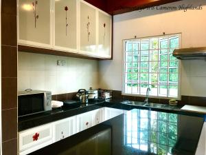 a kitchen with white cabinets and a black counter top at 21Homestay (3-Bedrooms) @ Iris Cameron Highlands in Cameron Highlands
