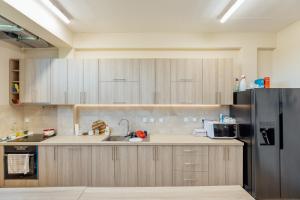 uma cozinha com armários de madeira e um frigorífico preto em Apartmani Luka em Herceg Novi