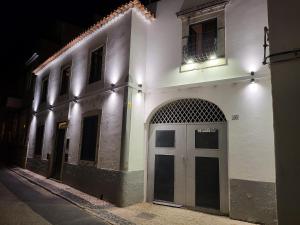 a white building with a door on a street at night at Faro Town House in Faro