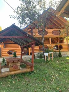 a wooden cabin with a table and a tree at Cottage Лісовий in Bukovets