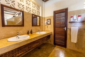 a bathroom with two sinks and a mirror at Zoi Boutique Hotel Zanzibar ex Sunshine Hotel in Matemwe