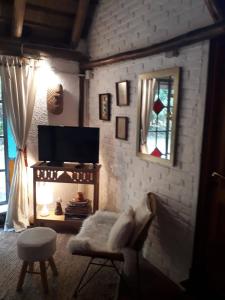 a living room with a flat screen tv and a chair at LA CABAÑA in Atlántida