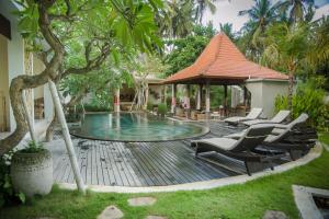 a swimming pool with chairs and a gazebo at Akatara Hotel in Nusa Penida
