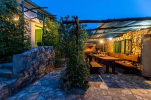 een patio met een houten tafel en een stenen muur bij Villa Lindraze in Dobrinj