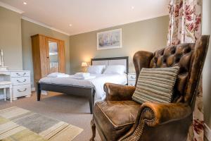 a bedroom with a bed and a leather chair at 4 Market Cross House Aldeburgh Air Manage Suffolk in Aldeburgh