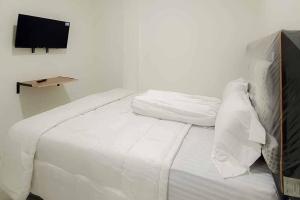 a white bed with white sheets and a television on a wall at Maminoti Syariah Residence Mitra RedDoorz in Bogor