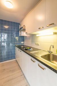 a kitchen with white cabinets and a sink and blue tiles at VilvoCity Center in Vilvoorde