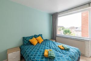 a bedroom with a bed with yellow pillows and a window at VilvoCity Center in Vilvoorde
