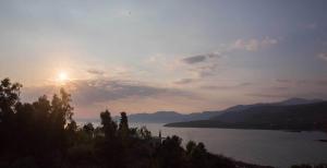 a sunset over a body of water with mountains at Remvi Hotel - Apartments in Stoupa