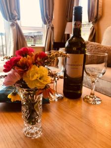 a bottle of wine and a vase with flowers on a table at Rymmon Retreat in Orkney