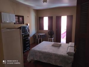 a small bedroom with a bed and a refrigerator at Suítes D'Belinha in Canoa Quebrada