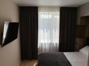 1 dormitorio con 1 cama y una ventana con cortinas en Апартаменты на Гагарина, en Cherkasy