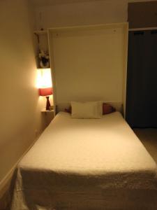Dormitorio pequeño con cama blanca y lámpara en NICE- GAIRAUT - JARDIN PRIVE- GRAND F1 LUMINEUX-Piscine Collective, en Niza