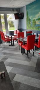 a dining room with red chairs and tables and a painting at Fasthotel Orléans Nord Artenay in Artenay