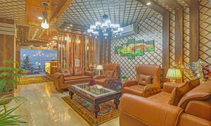 a living room with leather furniture and a chandelier at Hotel Woodville Inn Mcleodganj in McLeod Ganj