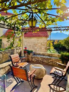 a patio with two benches and a pergola at Old town house with private garden in Budva