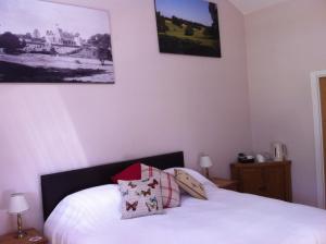 Schlafzimmer mit einem Bett mit weißer Bettwäsche und Kissen in der Unterkunft The Cholmeley Arms in Burton Coggles