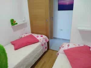 - 2 lits jumeaux dans une chambre avec des oreillers roses dans l'établissement Apartamento Peregrinos Por la Costa Camino Portugués As Casetas, à Rosal