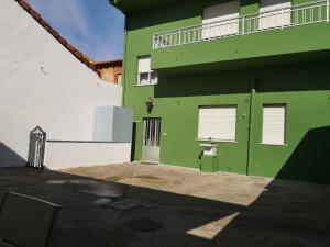 a green building with a door and a balcony at Casa de la Riva in Trobajo del Camino