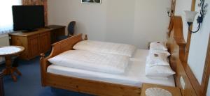 a bedroom with a bed with white sheets and a tv at Landhotel Gasthof Huber in Merching