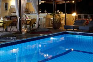 a swimming pool at night with a table and chairs at Hermes Hotel in Vromolimnos