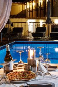 una mesa con 2 pizzas y velas junto a una piscina en Hermes Hotel en Vromolimnos