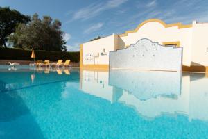 a swimming pool with blue water in front of a building at Carvoeiro, 2BR Pestana Gramacho Golf Apartment in Estômbar