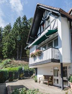 NiedersalweyにあるHaus am Waldのバルコニーとベンチ付きのホワイトハウスです。