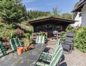 un patio con tavolo, sedie e una casa di Haus am Wald a Niedersalwey