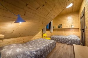 two beds in a room with wooden walls at Drevenica Emilka, 5 min Reštaurácia, Z terasy výhľad na Kráľovu hoľu a Polomské Očko, Gril, Ohnisko, Kotlík in Brezno
