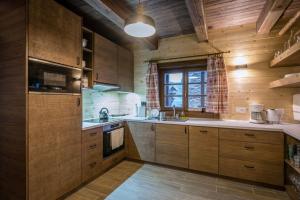 a large kitchen with wooden cabinets and a window at Drevenica Emilka-Kids playground-Outside shower-Washer-Views in Brezno