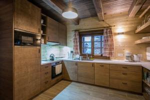 a large kitchen with wooden cabinets and a window at Drevenica Emilka - Sprcha, Záhradná hojdačka, Ohnisko in Brezno