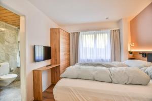 a bedroom with two beds and a television and a bathroom at Valaisia 125 in Riederalp