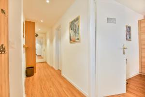 a hallway with white walls and a hard wood floor at Valaisia 125 in Riederalp