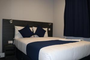 ein Schlafzimmer mit einem großen Bett mit blauen und weißen Kissen in der Unterkunft Blue Sapphire Hotel in London