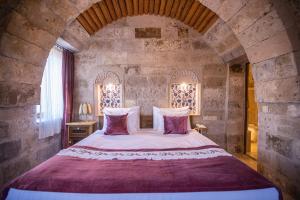a bedroom with a large bed in a stone wall at Şah Saray Cave Suites Halal Hotel in Göreme