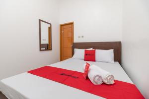 Una cama con toallas rojas y blancas. en RedDoorz Syariah near Summarecon Mall Bekasi en Kayuringin