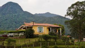 a house on a hill with mountains in the background at Fazenda Monte Verde A Morada do Muriqui in São Francisco Xavier