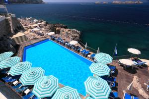 a swimming pool with blue and white umbrellas and the ocean at Apartments Mali Stradun in Dubrovnik