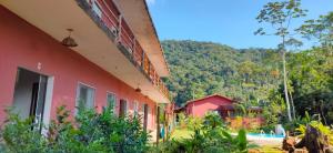 un bâtiment rouge avec une montagne en arrière-plan dans l'établissement Rancho Vista Verde, à Ubatuba