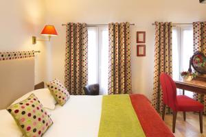 um quarto de hotel com uma cama, uma secretária e uma janela em New Orient Hotel em Paris
