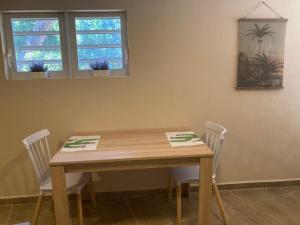 a wooden table with two chairs and two windows at Place2cu-Studio apartment in Willemstad +2 photos