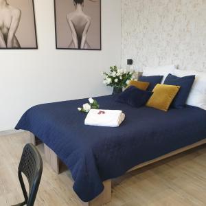 ein Bett mit einer blauen Decke und Blumen darauf in der Unterkunft Q Apart AMBER - garaż, Manufaktura klimatyzacja Netflix,FV STUDIO in Łódź